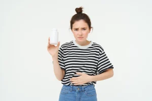 woman takes painkillers pills from stomach ache menstrual pain holds hand belly shows bottle with
