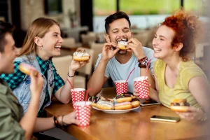 group cheerful friends eating donuts cafe