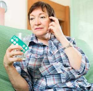 serious mature woman with pills glass water