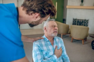 dark haired doctor bending towards mature caucasian man with chest pain
